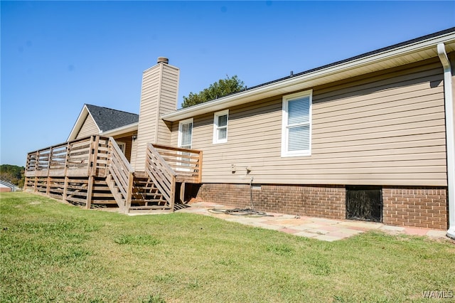 rear view of house featuring a lawn and a wooden deck