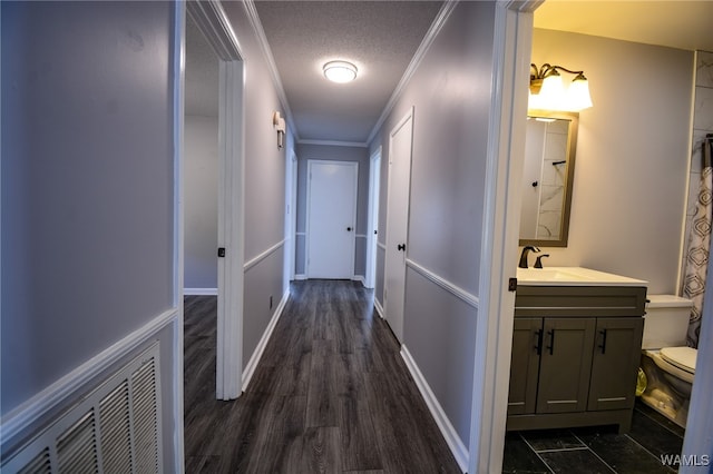 hall featuring crown molding, dark hardwood / wood-style flooring, and a textured ceiling