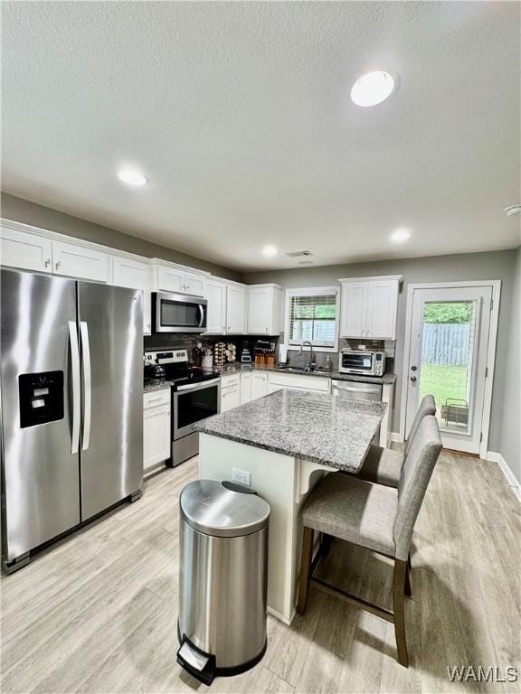 6643 Cooperstown Cir, Tuscaloosa, AL 35453 - kitchen with stainless steel appliances, light wood-type flooring, a sink, a kitchen island, and white cabinetry