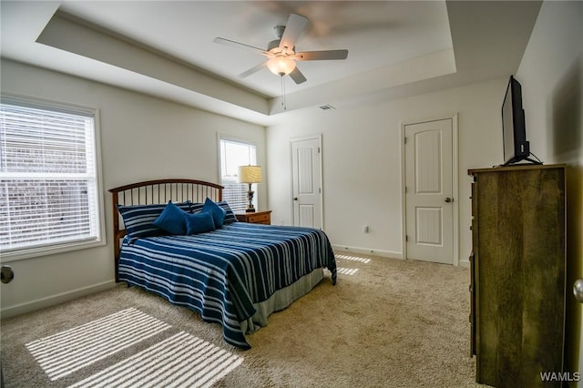 bedroom featuring a tray ceiling, carpet, visible vents, and baseboards