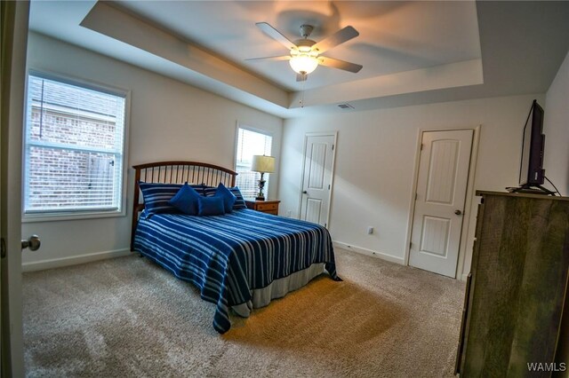 bedroom featuring a tray ceiling, carpet flooring, visible vents, and baseboards