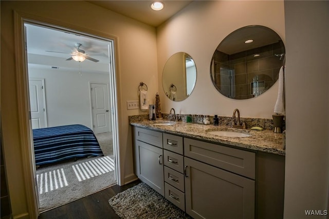 bathroom featuring a ceiling fan, double vanity, a sink, and wood finished floors