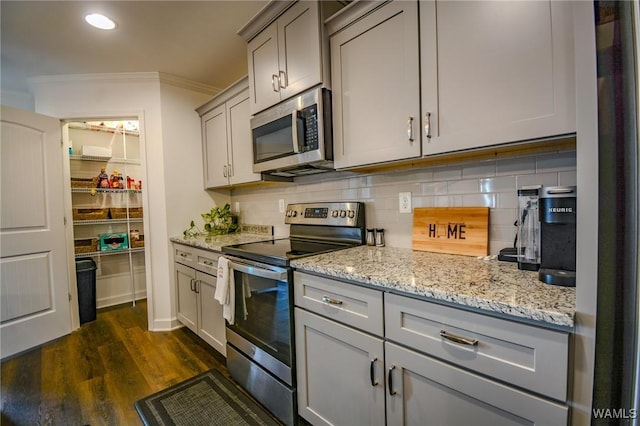 kitchen featuring dark wood-style floors, crown molding, tasteful backsplash, gray cabinetry, and appliances with stainless steel finishes