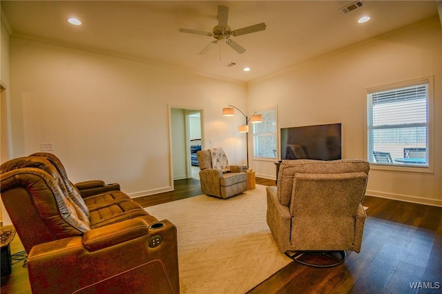 living room featuring baseboards, wood finished floors, visible vents, and crown molding