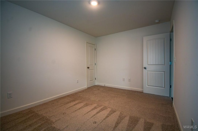 carpeted spare room featuring baseboards