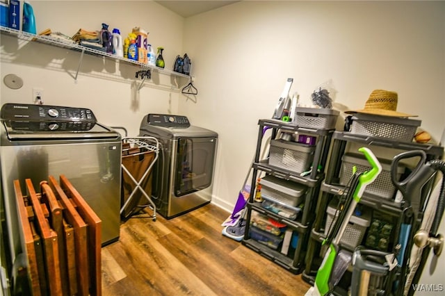 clothes washing area featuring laundry area, washer and clothes dryer, and wood finished floors