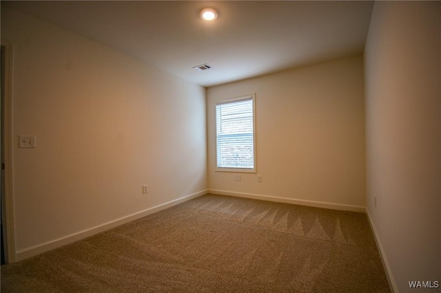 carpeted spare room with visible vents and baseboards