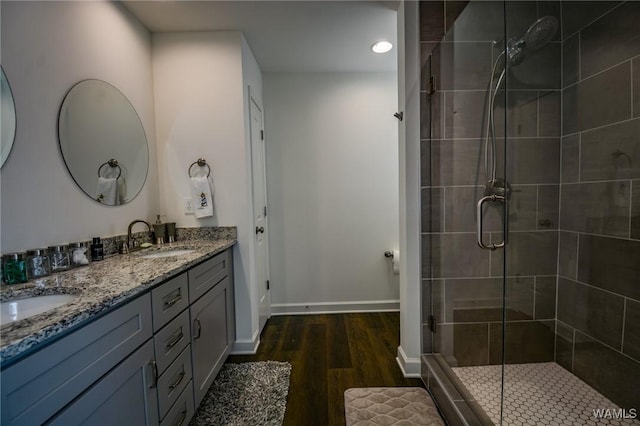 full bathroom with a sink, a shower stall, baseboards, and wood finished floors