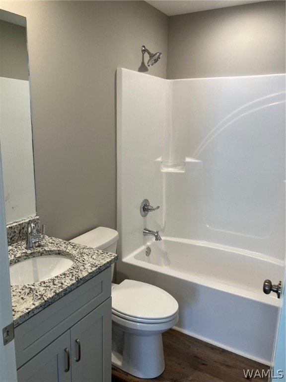 full bathroom featuring toilet, wood-type flooring, vanity, and bathing tub / shower combination