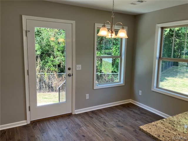 entryway with a chandelier, plenty of natural light, and dark wood-type flooring