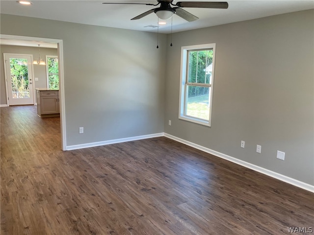 unfurnished room featuring ceiling fan with notable chandelier and dark hardwood / wood-style floors