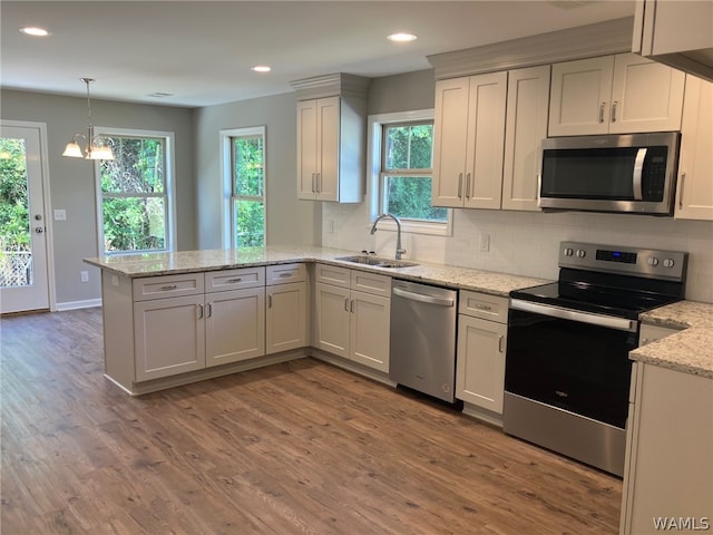 kitchen with white cabinets, sink, hardwood / wood-style flooring, kitchen peninsula, and stainless steel appliances