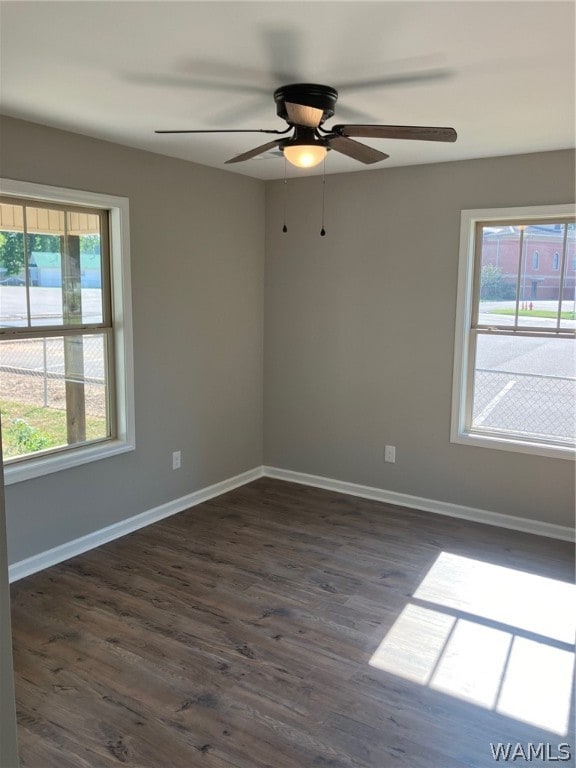 empty room featuring a wealth of natural light, dark hardwood / wood-style flooring, and ceiling fan