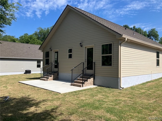 rear view of property featuring a lawn, cooling unit, and a patio