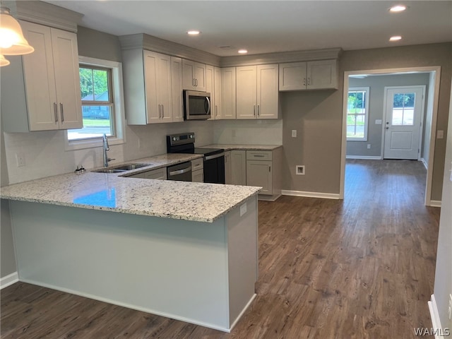 kitchen featuring light stone countertops, sink, stainless steel appliances, kitchen peninsula, and pendant lighting