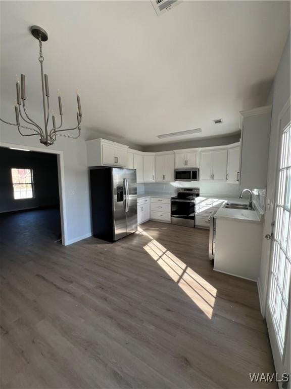 kitchen with white cabinetry, sink, hanging light fixtures, stainless steel appliances, and a chandelier