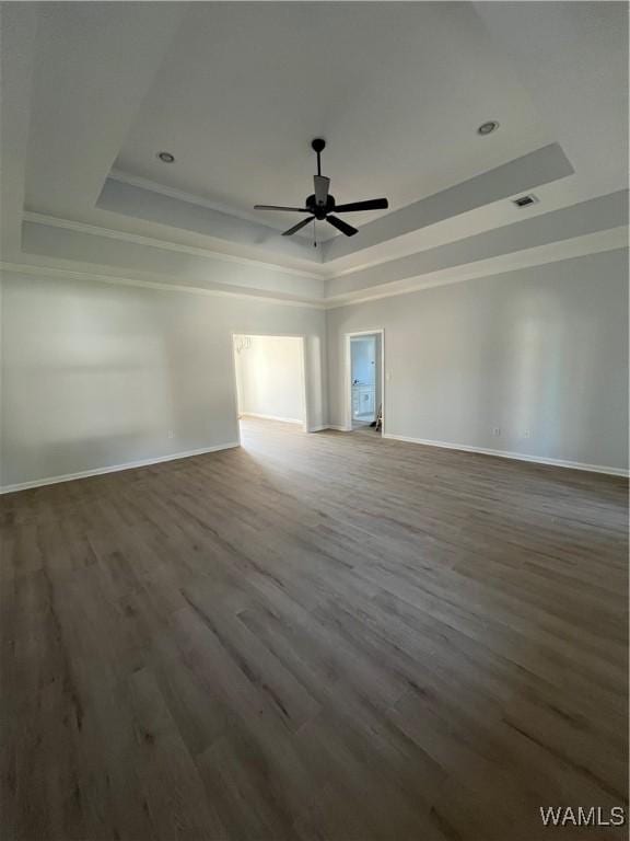 empty room featuring dark hardwood / wood-style floors, ceiling fan, and a tray ceiling