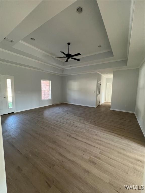 interior space with a tray ceiling, ceiling fan, ornamental molding, and hardwood / wood-style flooring