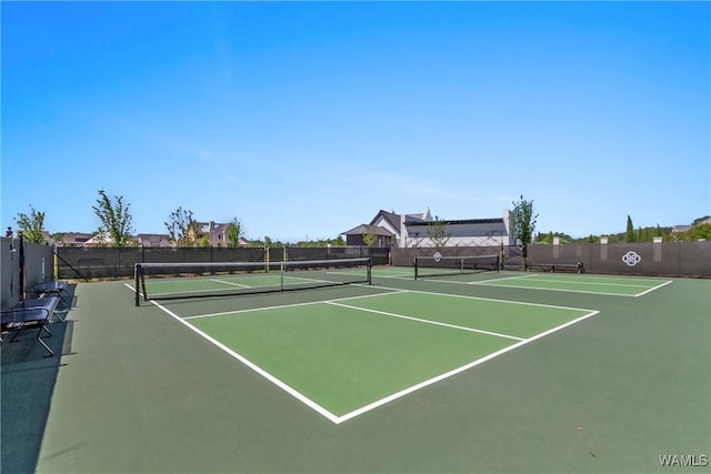 view of tennis court featuring community basketball court and fence