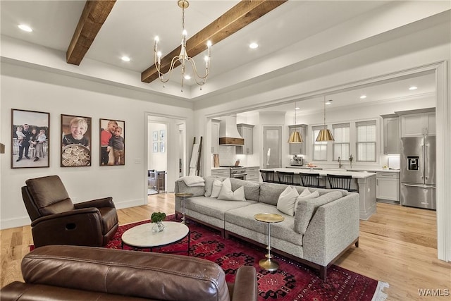 living area with beam ceiling, recessed lighting, light wood-style flooring, and an inviting chandelier