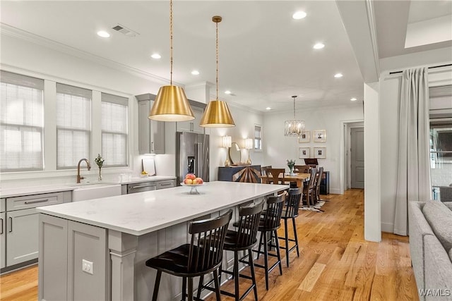 kitchen with visible vents, a kitchen island, gray cabinets, stainless steel appliances, and a sink