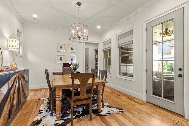 dining space with light wood-style flooring, baseboards, a notable chandelier, and ornamental molding