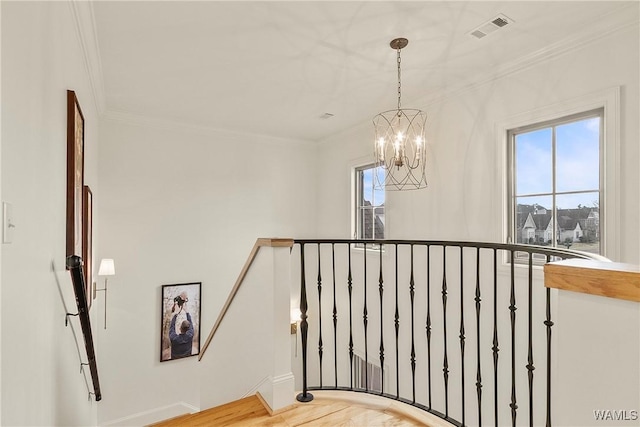 stairway with visible vents, wood finished floors, a notable chandelier, and ornamental molding