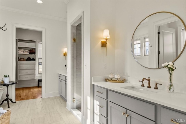 full bath with vanity, crown molding, a spacious closet, and a shower