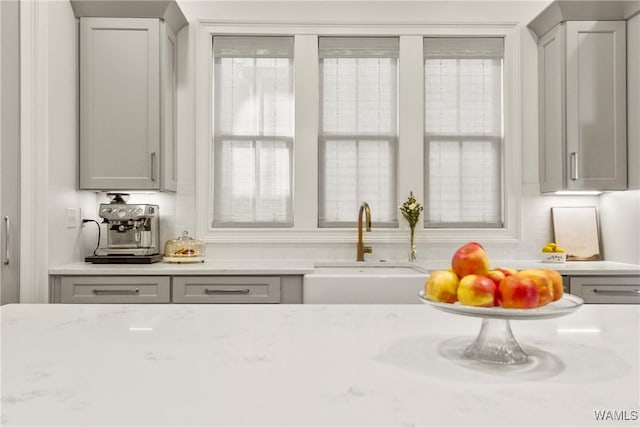 interior space featuring light stone counters, gray cabinetry, and a sink