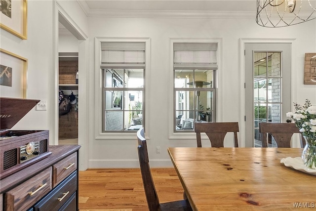 dining area with a healthy amount of sunlight, light wood-style floors, and ornamental molding