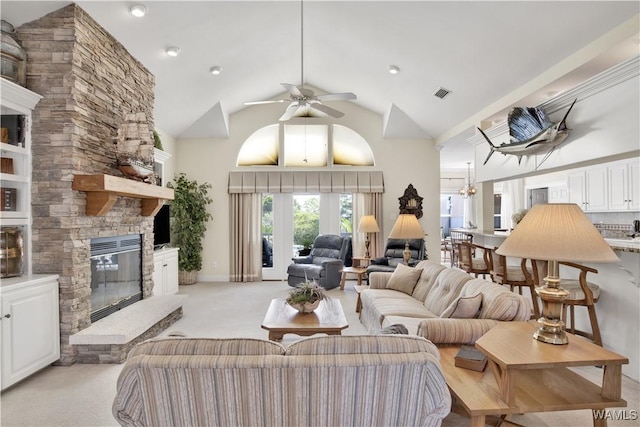 living area with a fireplace, visible vents, a ceiling fan, light carpet, and high vaulted ceiling