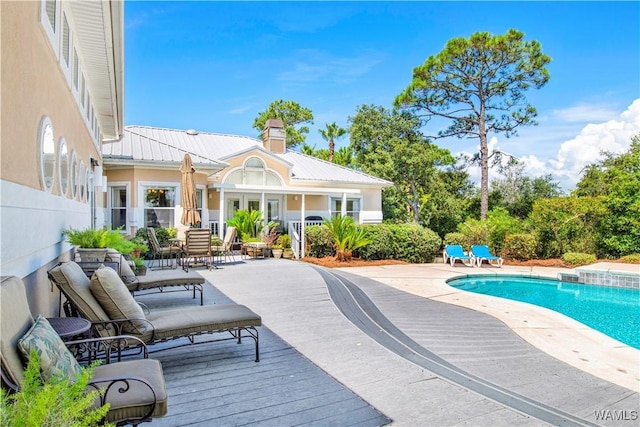 outdoor pool featuring a deck, a patio, and fence