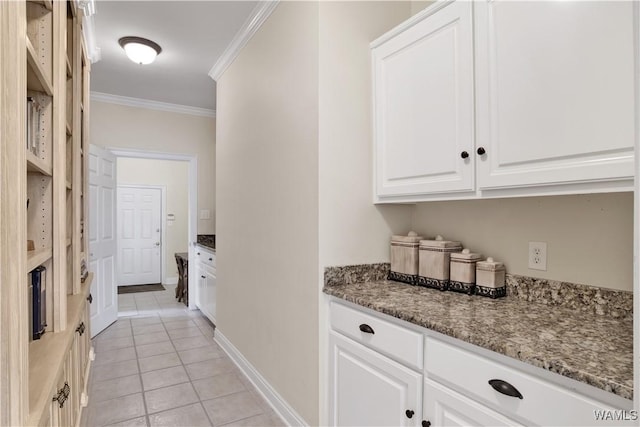 bar featuring light tile patterned floors, ornamental molding, and baseboards