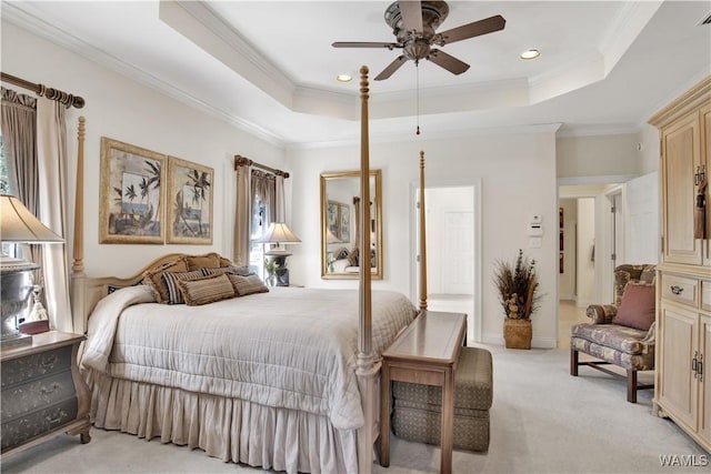 bedroom with ceiling fan, a tray ceiling, ornamental molding, and light colored carpet