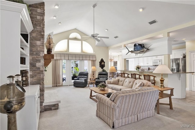 living area with high vaulted ceiling, ceiling fan with notable chandelier, visible vents, and light colored carpet