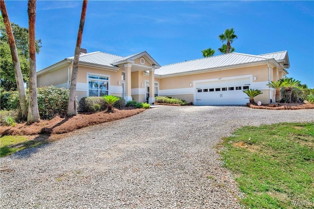 view of front of property featuring metal roof, gravel driveway, and stucco siding