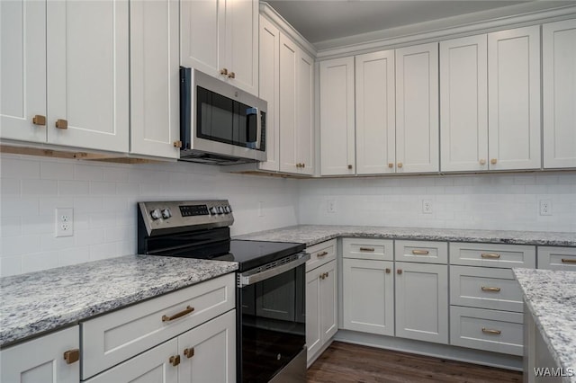 kitchen with dark hardwood / wood-style floors, light stone countertops, appliances with stainless steel finishes, tasteful backsplash, and white cabinetry