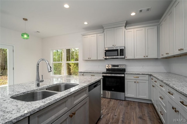 kitchen with sink, stainless steel appliances, light stone counters, dark hardwood / wood-style floors, and decorative light fixtures