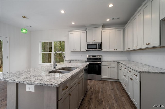 kitchen with sink, hanging light fixtures, dark wood-type flooring, stainless steel appliances, and light stone counters