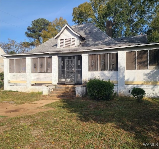 bungalow-style home featuring a sunroom and a front yard