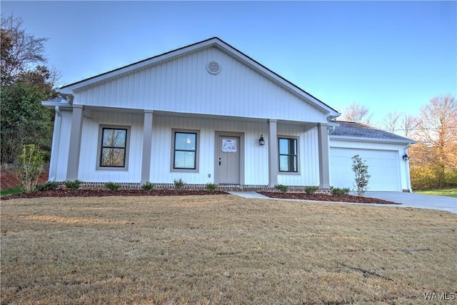 view of front of home featuring a front yard, an attached garage, a porch, and driveway