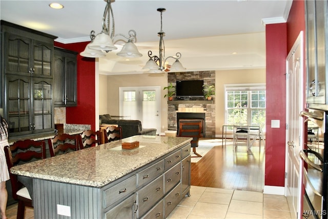 kitchen with light stone counters, pendant lighting, light hardwood / wood-style flooring, a fireplace, and a center island