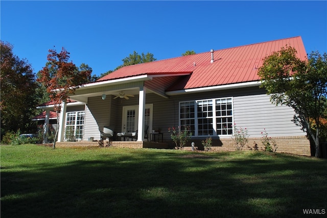 back of house with ceiling fan and a yard