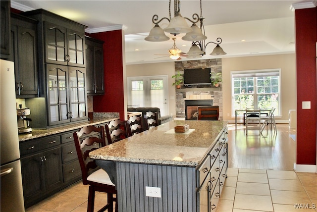 kitchen featuring a center island, light hardwood / wood-style flooring, stainless steel fridge, pendant lighting, and a breakfast bar area