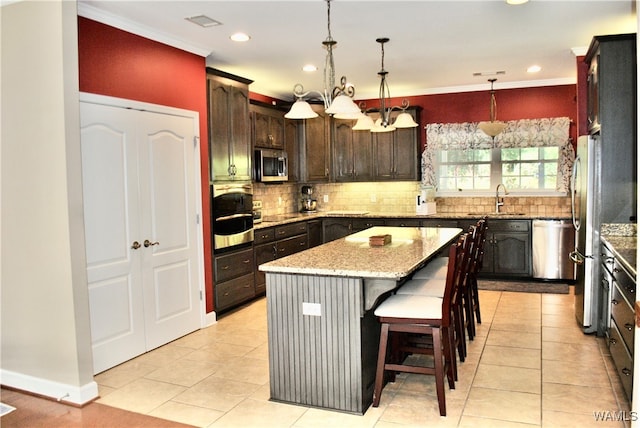 kitchen featuring a center island, sink, stainless steel appliances, backsplash, and pendant lighting