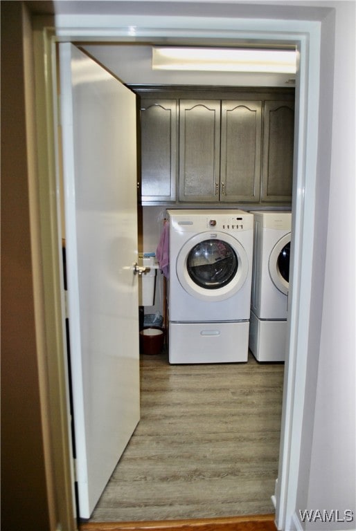 clothes washing area featuring light hardwood / wood-style floors, cabinets, and independent washer and dryer