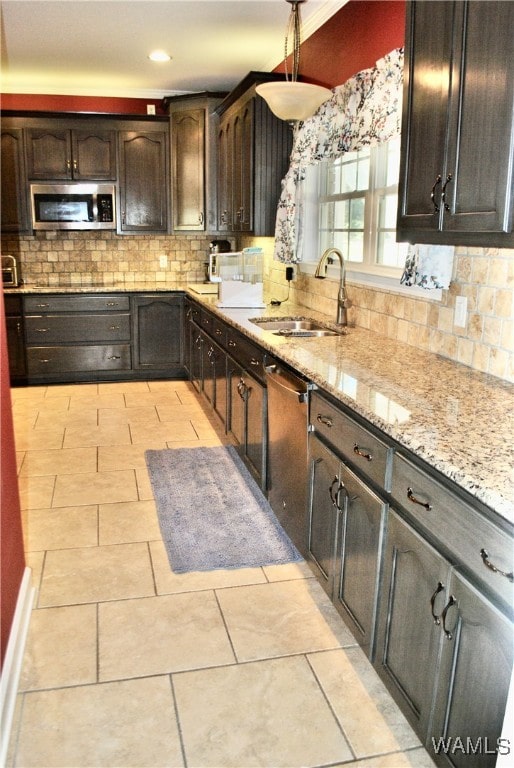 kitchen featuring backsplash, sink, light stone countertops, appliances with stainless steel finishes, and dark brown cabinetry