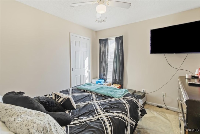 carpeted bedroom with ceiling fan and a textured ceiling