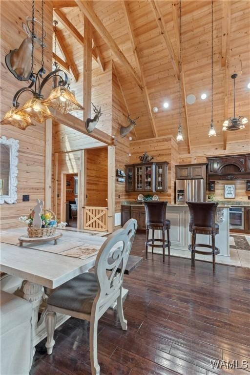 dining room featuring beam ceiling, wooden ceiling, wood walls, and dark wood-type flooring