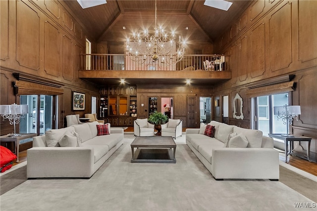 living room with high vaulted ceiling, wooden walls, a skylight, wood ceiling, and a chandelier